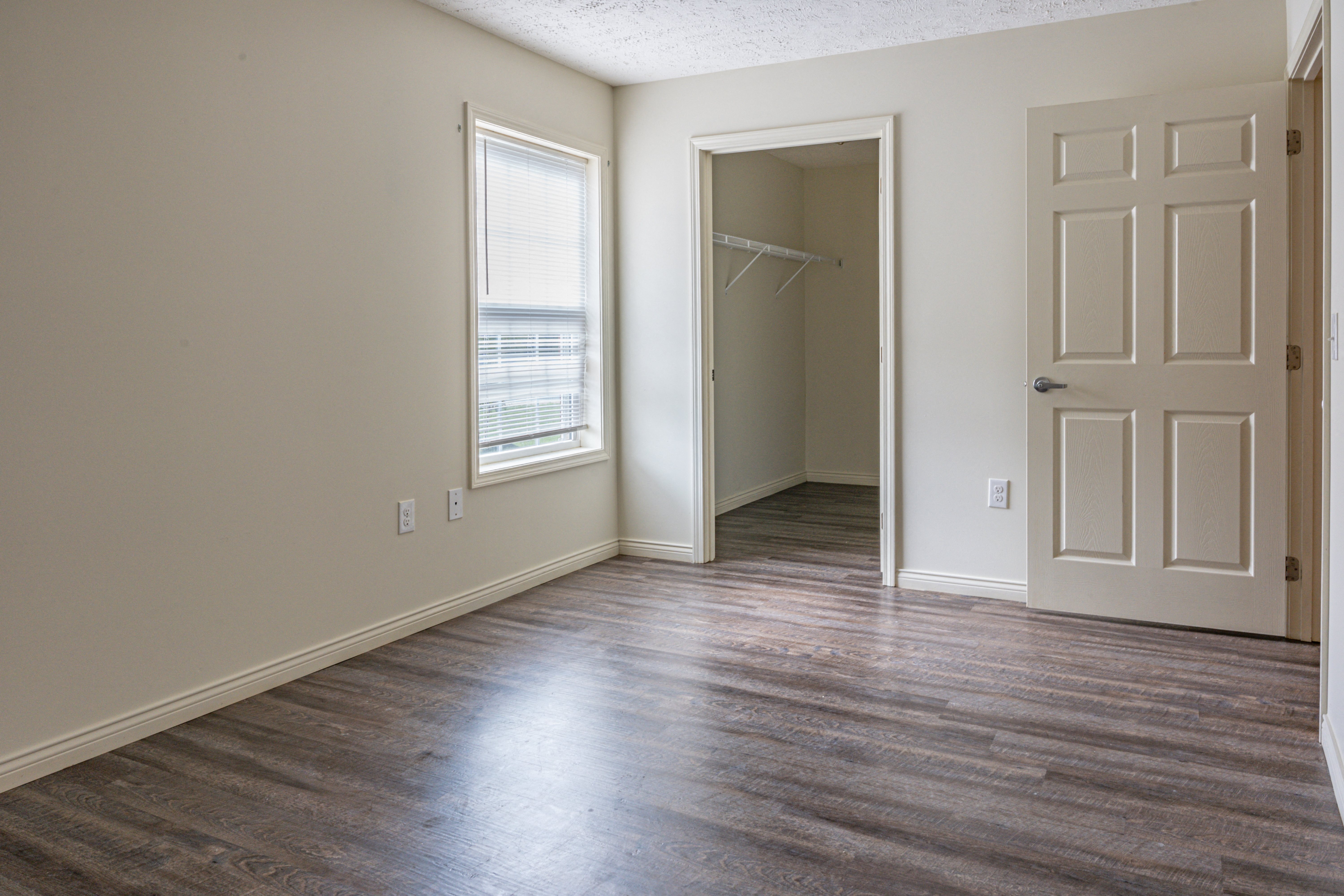 an empty living room with wood floors and a white door